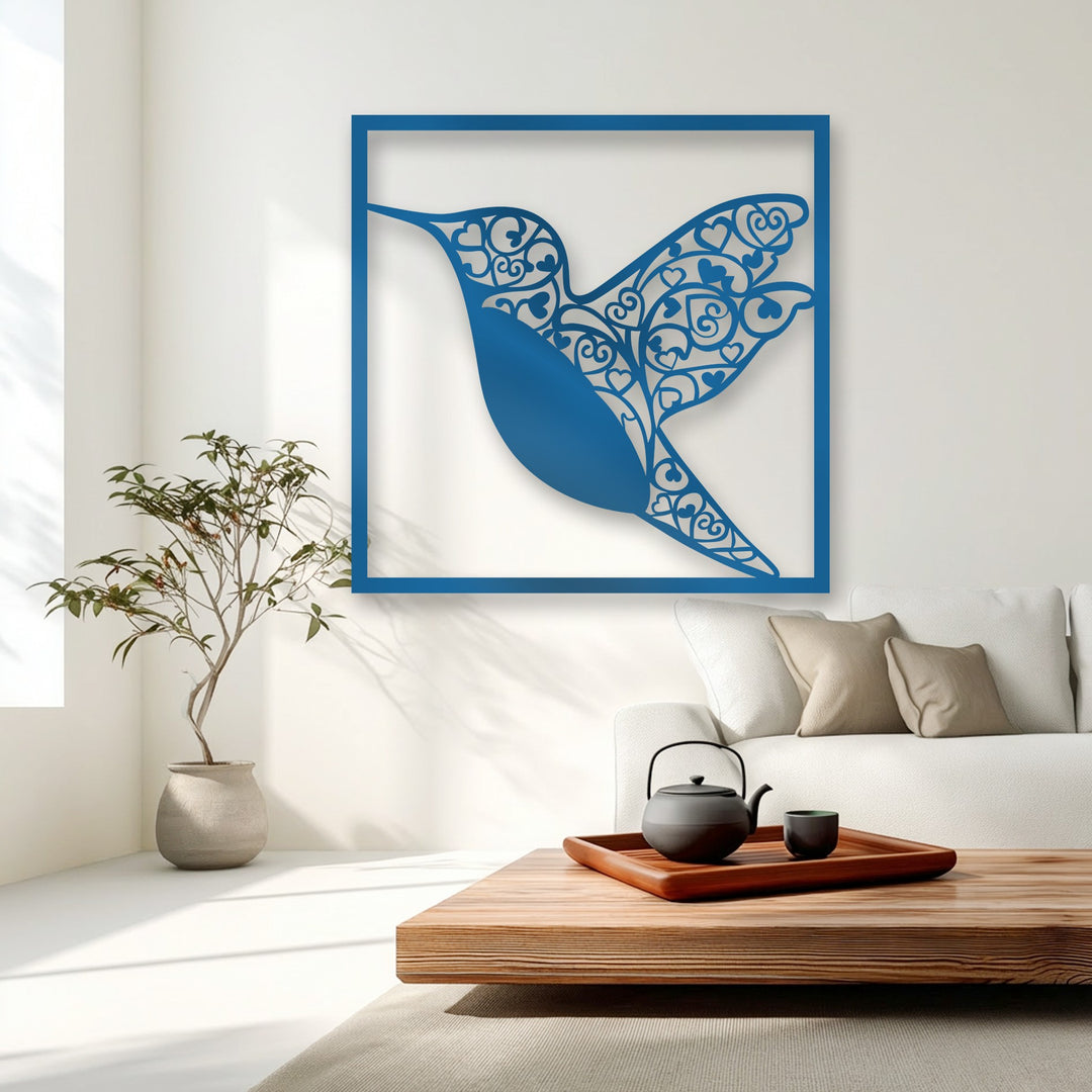 The graceful, stylized hummingbird metal wall decor features intricate organic heart patterns on its wings, creating a vibrant blue focal point.