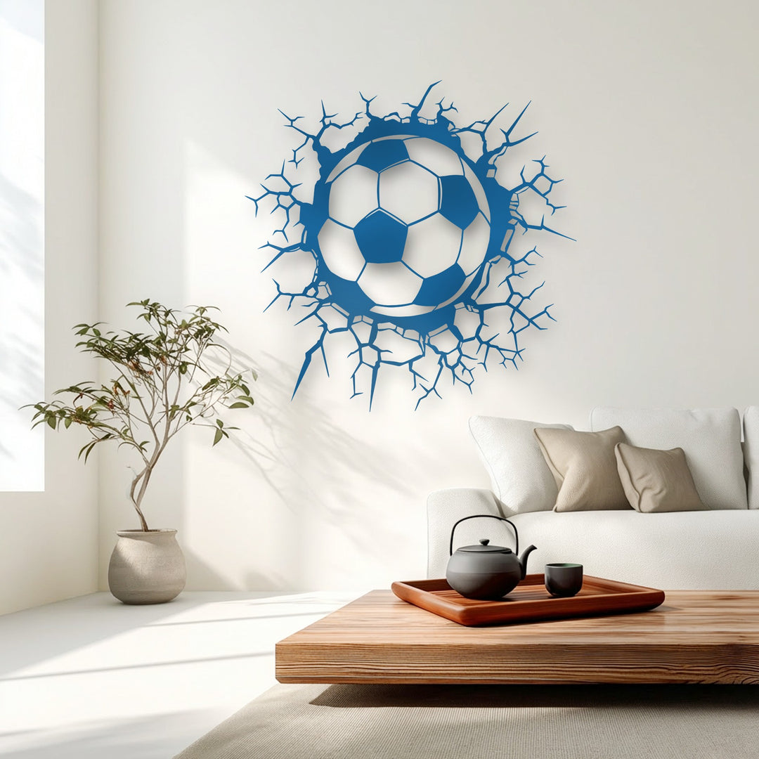 Vibrant blue soccer ball metal artwork appears to burst through a pristine white wall, creating a dynamic breaking wall design.