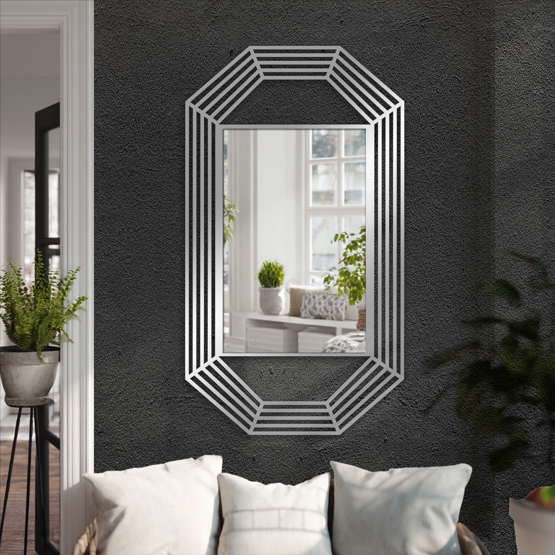 Dominated by black, a modern decorative mirror with an octagonal metal frame reflects a bright room, contrasting beautifully with the dark metal wall decor.