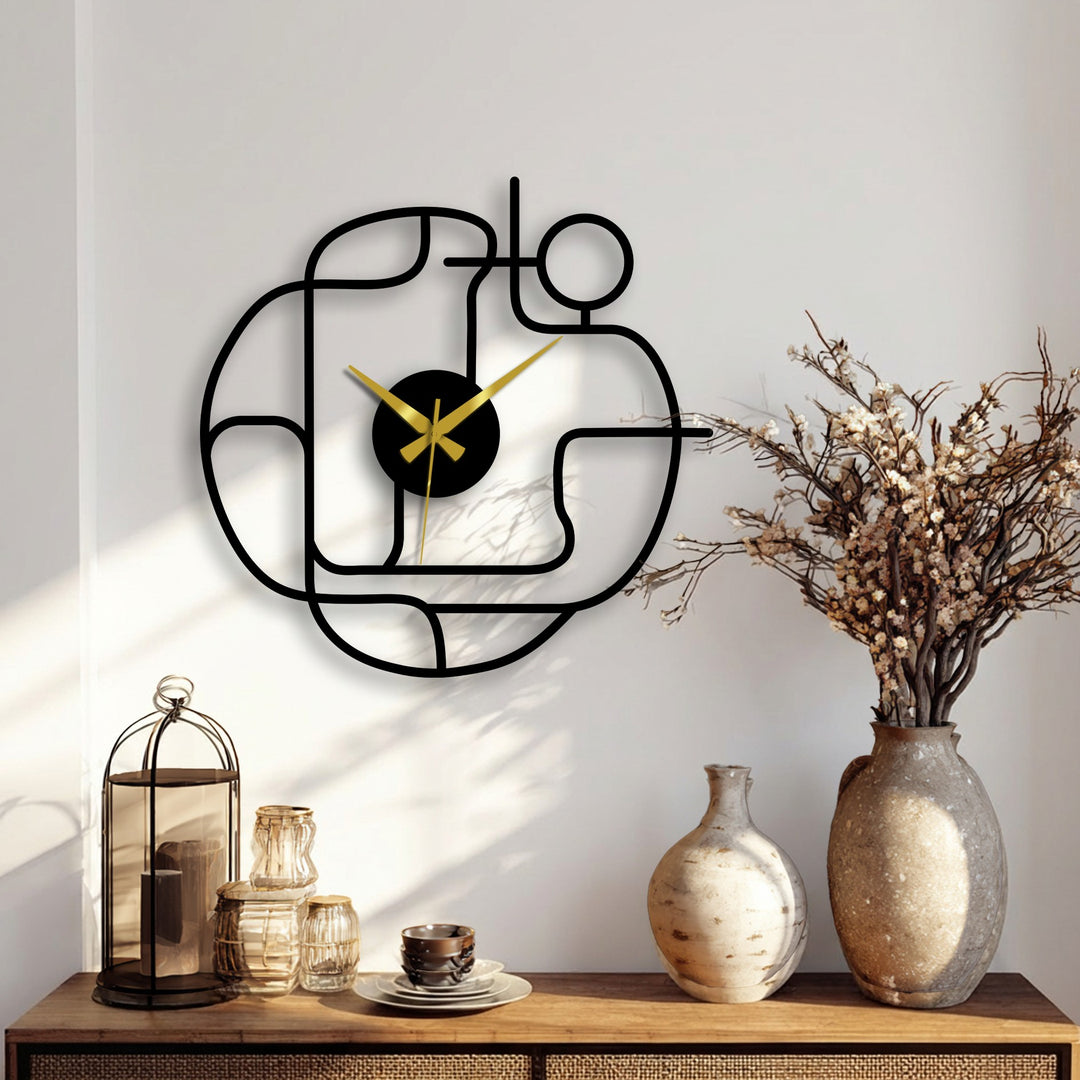 Bold gold clock hands offer striking color contrast against the black frame of this abstract continuous line modern metal wall clock, a stylish piece of home decor.