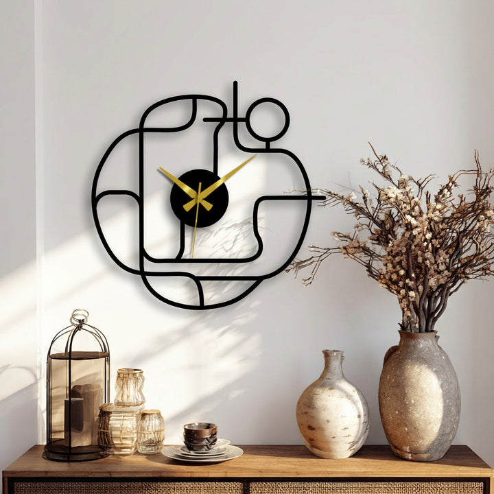 Bold gold clock hands offer striking color contrast against the black frame of this abstract continuous line modern metal wall clock, a stylish piece of home decor.