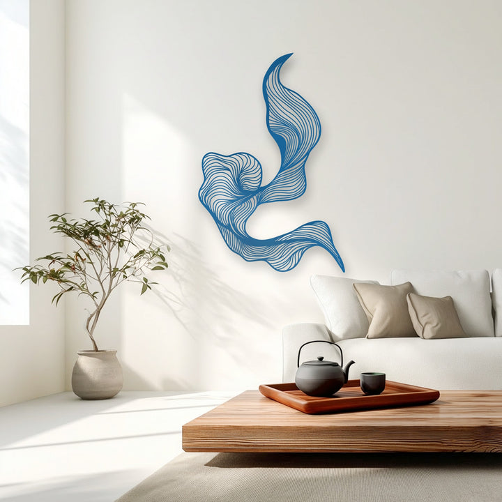 A vertically oriented, fluidly shaped abstract metal wall decor piece featuring vibrant blue flowing lines adorns a pristine white wall.