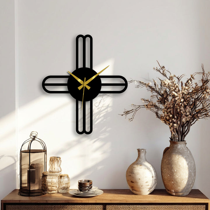 Moderate color saturation highlights the minimalist metal artwork of a modern cross line wall clock with gold hands against a neutral wall.