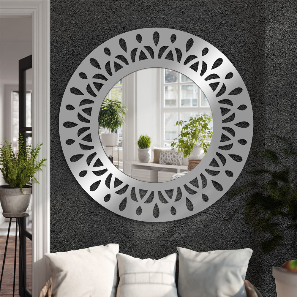 Shadows accentuate the leaf motifs cut into the silver-tone framed wall mirror, creating a play of light that enhances its modern statement design.