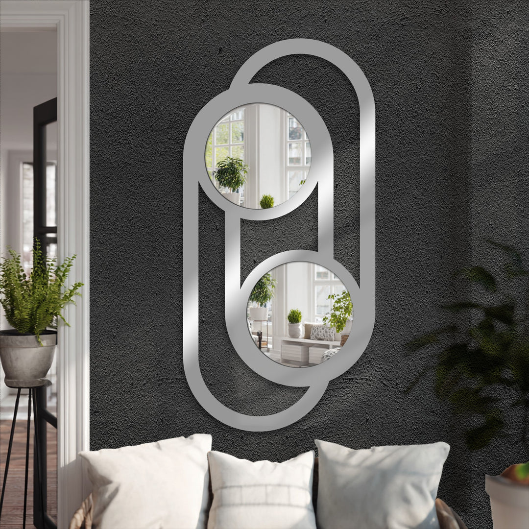 Textured dark gray wall behind the double circle link metal artwork provides a striking backdrop for the modern bathroom mirror.