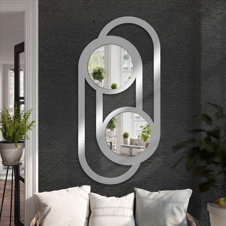 Textured dark gray wall behind the double circle link metal artwork provides a striking backdrop for the modern bathroom mirror.