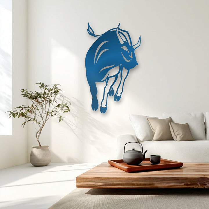 The minimalist background features clean white walls illuminated by natural light, enhancing the vibrant blue decorative metal art of a charging bull.