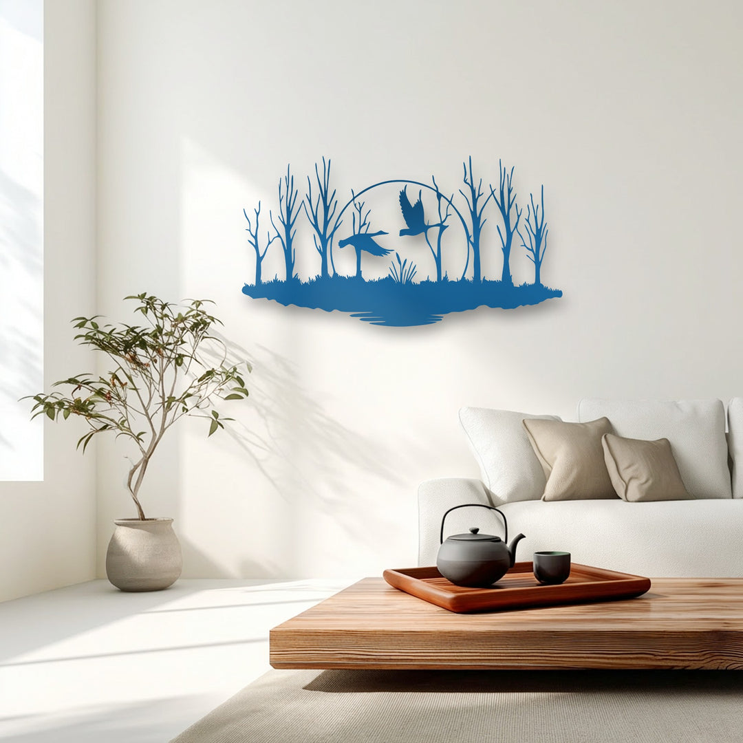 The organic, fluid lines of a deep blue metal artwork depict a serene forest with graceful flying birds above calm water.