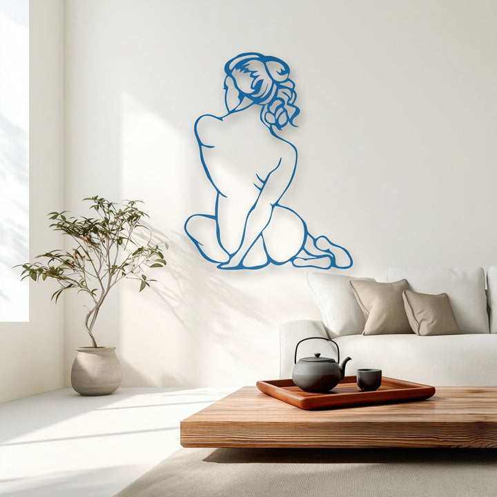 A dark matte black teapot and cup on a wooden tray beautifully complement the serene blue decorative metal art of a silent female figure.