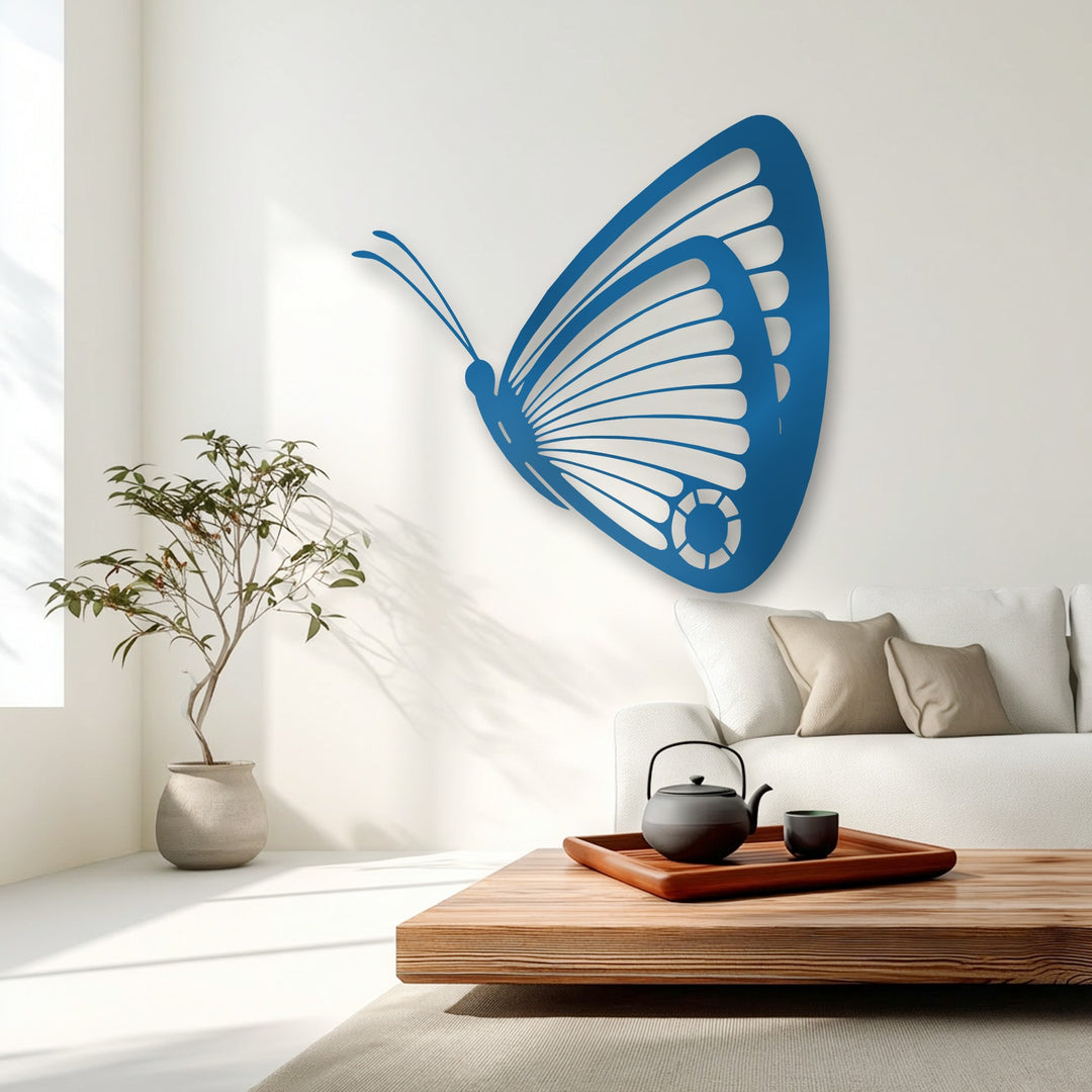 Soft, plush beige pillows rest on a pristine white sofa, complementing the sleek blue butterfly unique metal wall art that graces the bright wall.