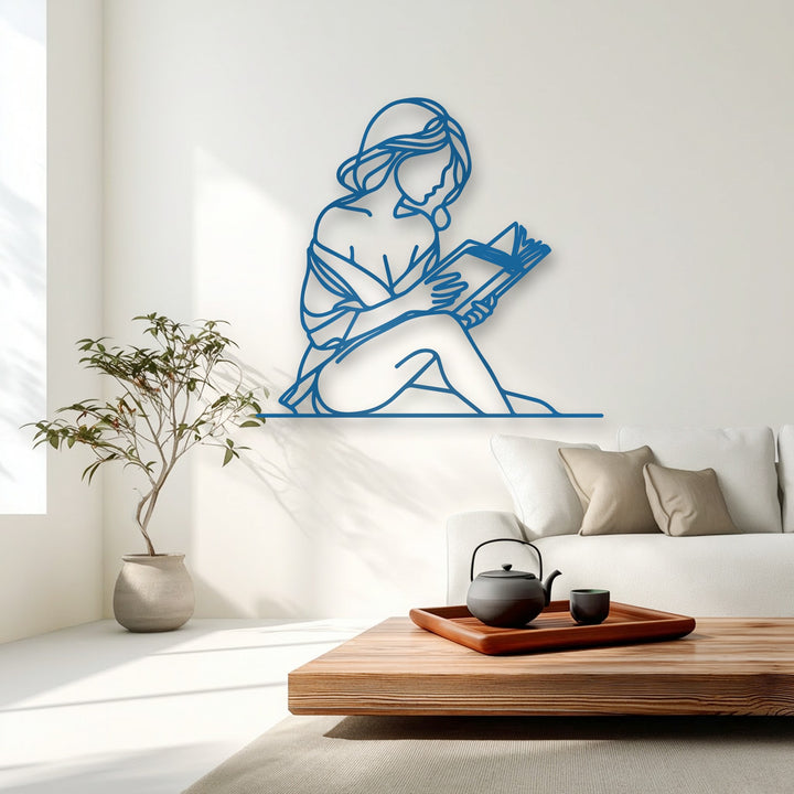 The vivid azure outline of the minimal woman reader metal art for wall sharply contrasts against the pristine white background, highlighting its elegant form.