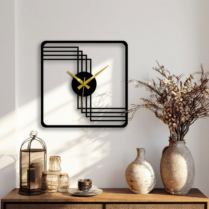 Featuring a bold black square frame, this decorative metal art clock presents a geometric design with gold hands, serving as the loudest element in the setting.