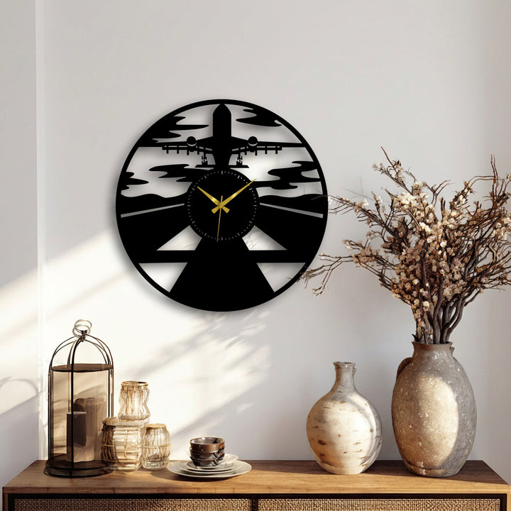 A sunlit wooden table in the foreground features a metal lantern and glass items, complementing the airplane silhouette metal artwork.