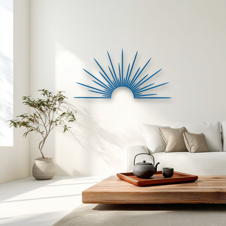The focal point is a vibrant blue sunburst minimal metal art for wall, radiating modern decor on the bright white interior wall.