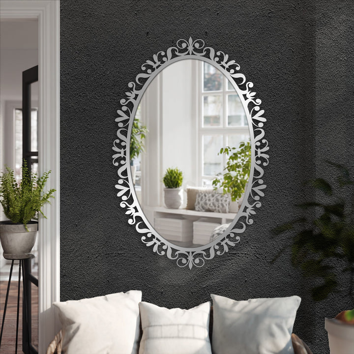 Light reflects off the mirror for wall decor framed with a dark, textured wall, creating a strong color contrast that accentuates its floral scrollwork.