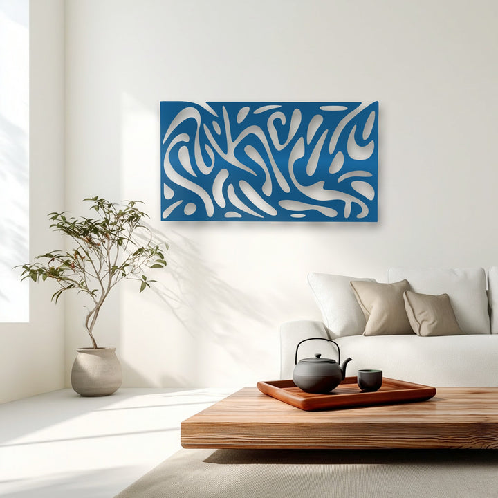 The decorative metal art, an azure abstract fluid pattern, creates engaging depth with its cut-out forms and cast shadows on the layered white wall.