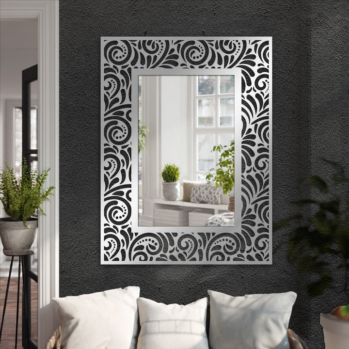 Muted color saturation highlights the dark floral scroll pattern on this ornate rectangular framed wall mirror, an elegant and sophisticated piece of metal artwork.