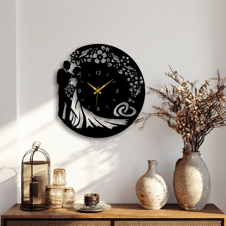 The bold color contrast of the black romantic bride & groom wedding silhouette metal artwork clock stands out vividly against the light wall.
