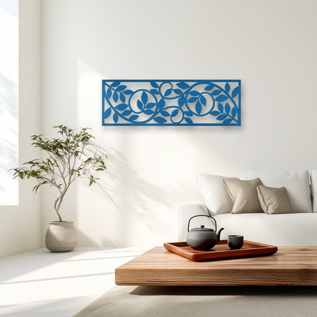 The sleek geometric form of the blue rectangular metal artwork features an intricate flowing botanical vine pattern.