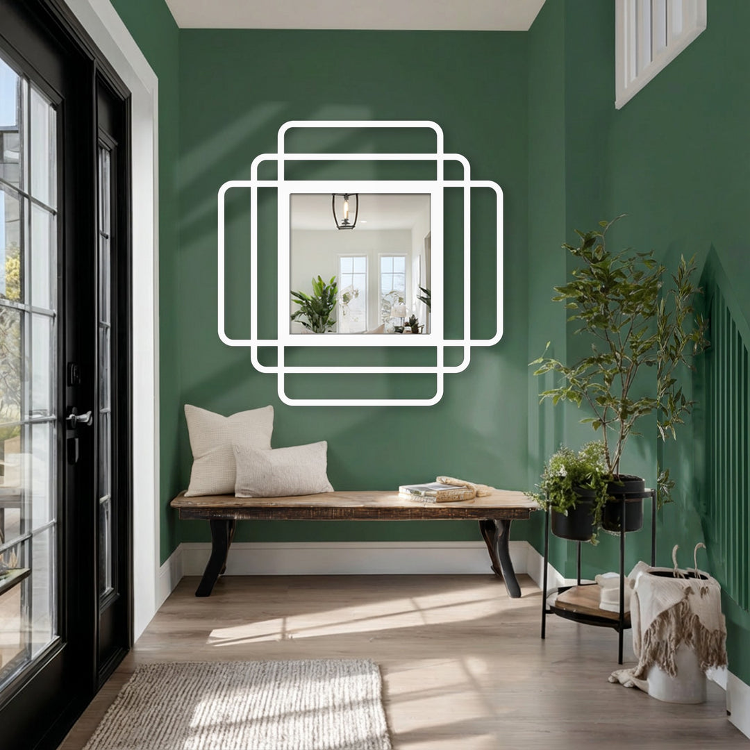 Against the backdrop of deep green walls, a decorative mirror with layered white frames sits above a wooden bench, enhancing the room's design.