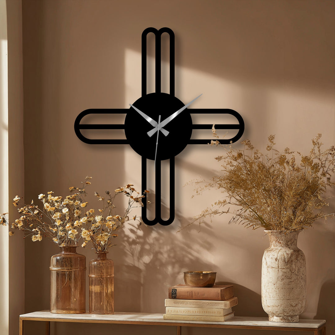 Foreground shadows highlight the minimalist cross line's sharp angles and curves, emphasizing the metal wall decor’s juxtaposition against the beige wall.