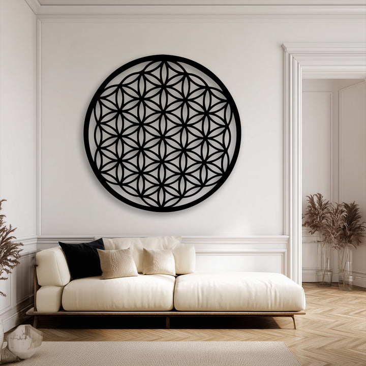 The smooth, matte surface of the black Flower of Life metal art for wall stands out against the finely textured upholstered sofa and the subtly ribbed rug.
