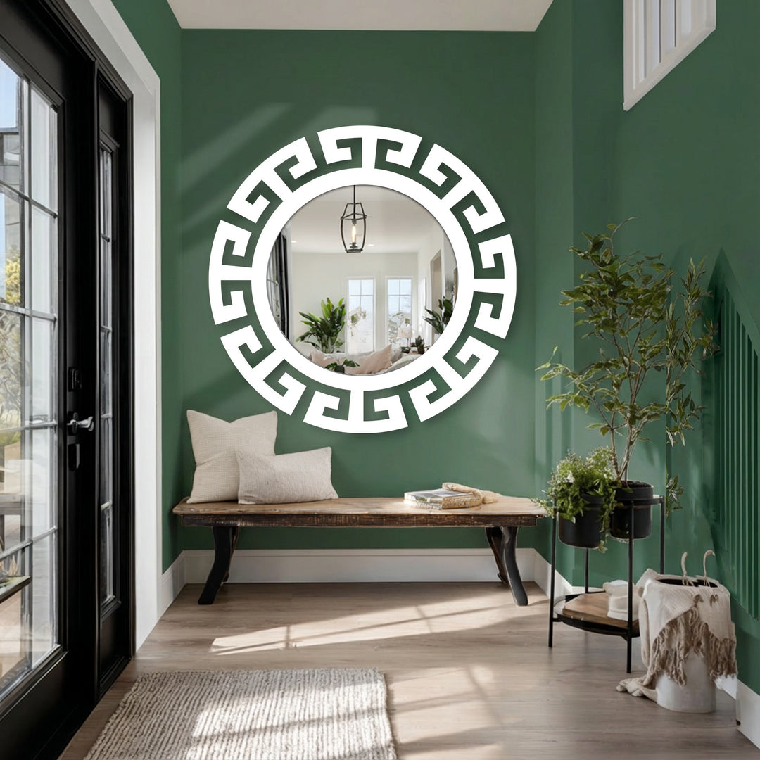 Against the green background, a modern mirror with a Greek key frame is showcased above a wooden bench in this scene featuring unique metal wall art.