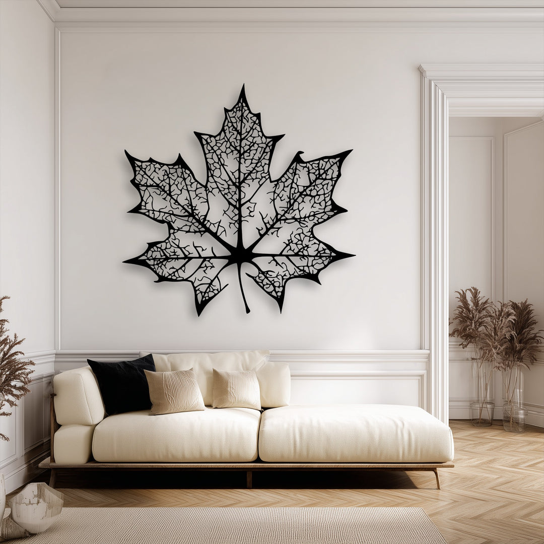The organic forms of an intricate maple leaf silhouette, a decorative metal art piece with detailed veins, cast shadows on a white wall above a sofa.
