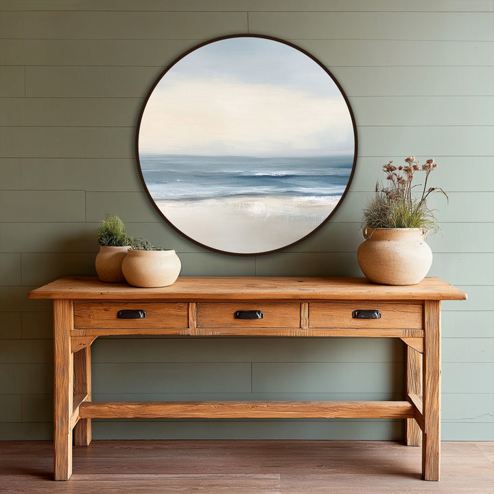 Showing the realistic detail of the oil painting wall art, a round coastal painting features a serene tide meeting the sandy shore.