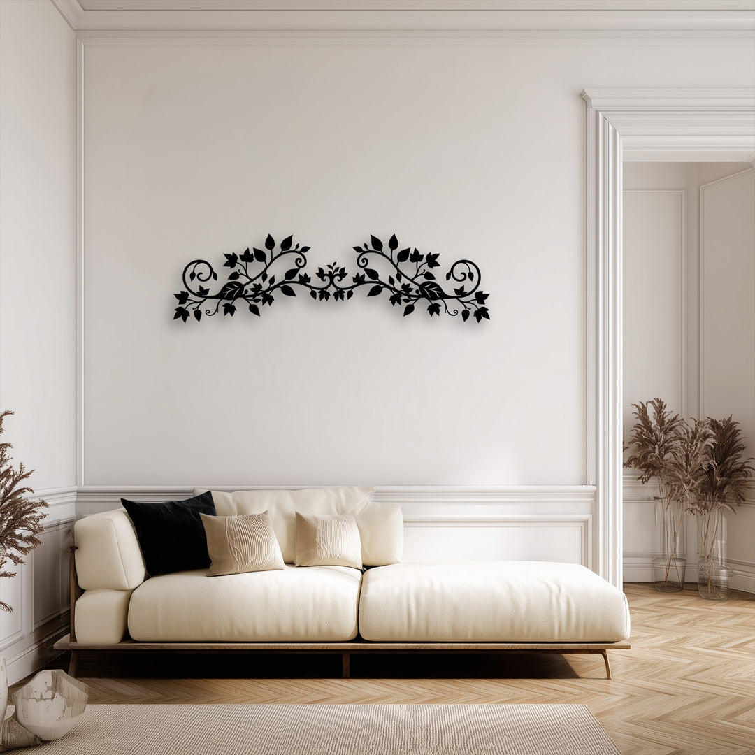 An elegant black floral vine decorative metal art piece with intricate scrollwork, centered above a cream sofa on a pristine white wall.