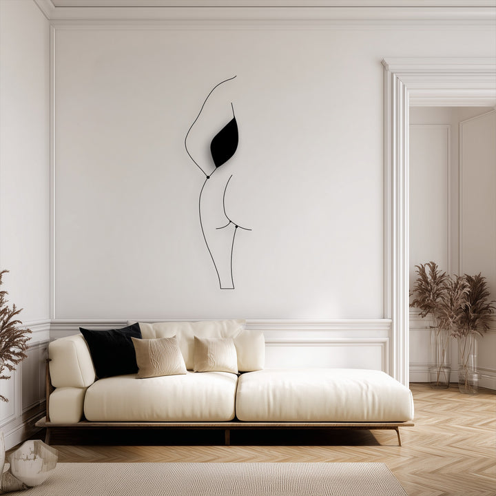 The elegant background features a white wall with classic molding and a warm wooden floor, subtly showcasing the minimalist female silhouette decorative metal art.