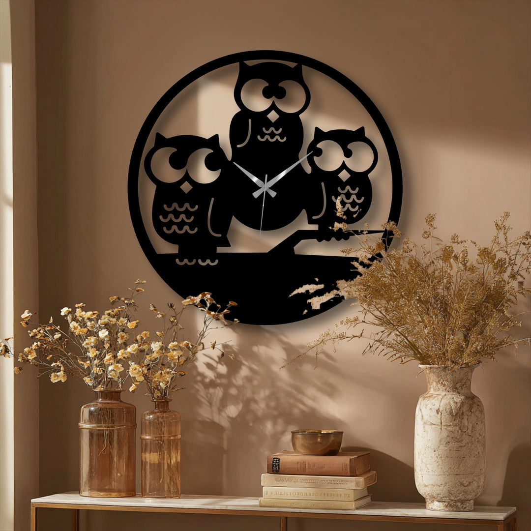 The distinct layering effect is showcased by the decorative metal art clock's three owl silhouette design, casting shadows on the wall.