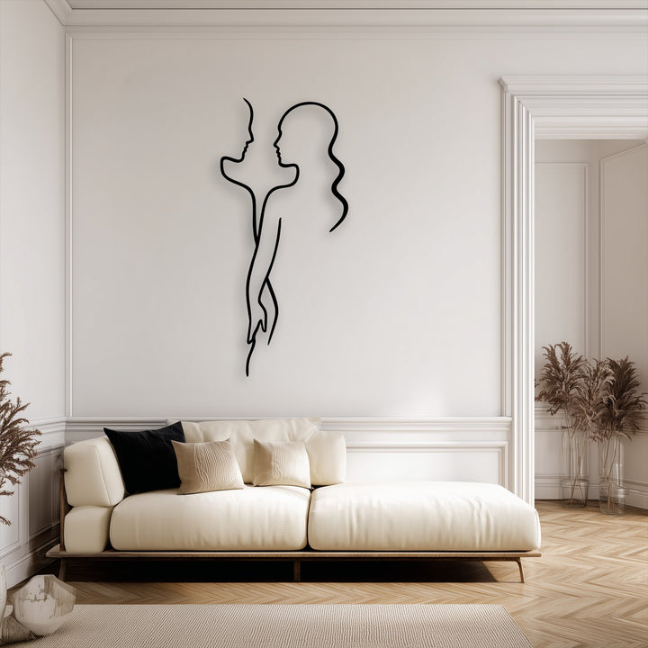 A minimalist black metal wall decor featuring abstract profiles of two figures subtly intertwined, creating a modern love silhouette above a cream sofa.
