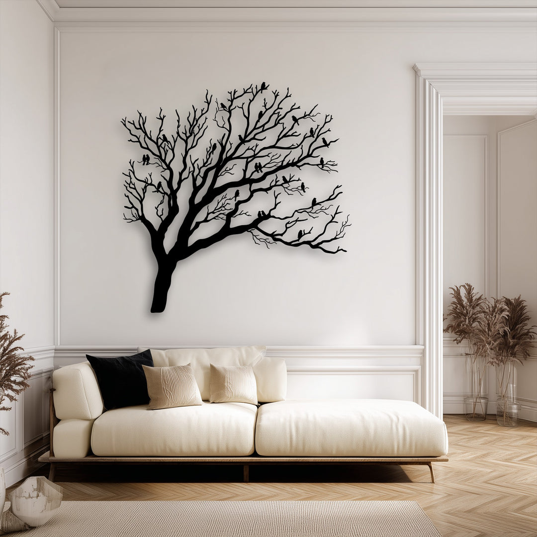 A desaturated interior showcases a stark Birds on Bare Tree Branches nature silhouette metal artwork above a cream sofa.