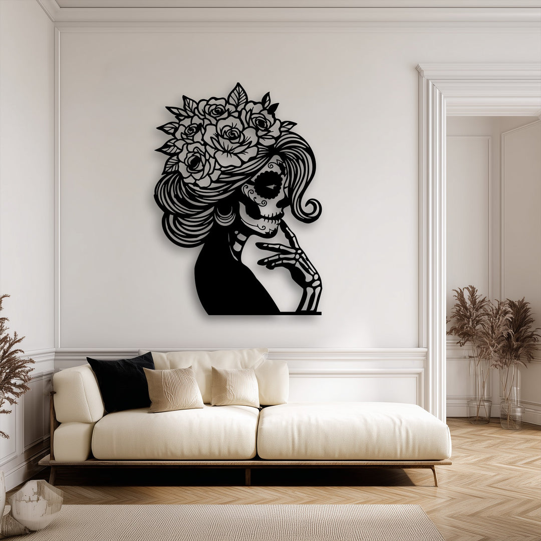 The realistic detail of this decorative metal art depicts an intricate black floral sugar skull lady on a crisp white wall above a cream sofa.
