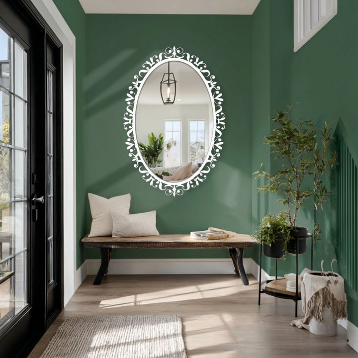 Vertically oriented oval framed wall mirror featuring ornate floral scrollwork adds a touch of elegance to any space with its unique shape.