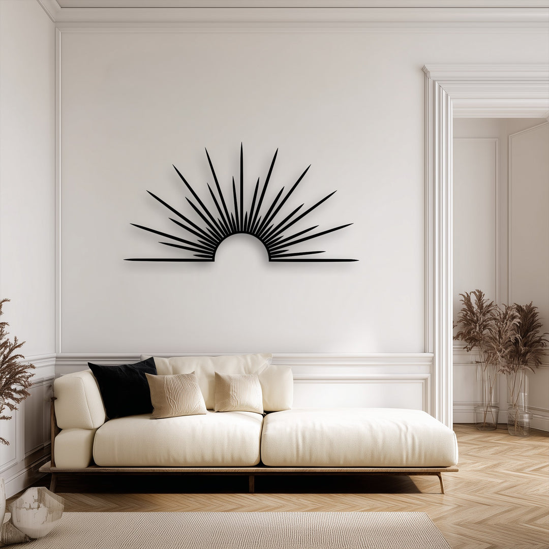 Dominating the clean white wall, a striking black sunburst minimalist decorative metal art piece hangs above a cream sofa.