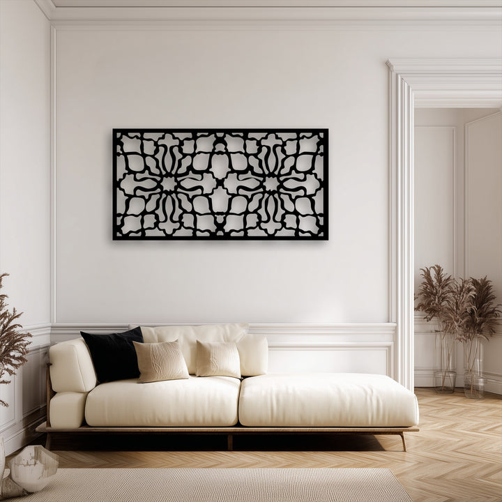 A creamy sofa resting on a textured beige rug with a unique vase of dried decor in the foreground, below the striking ornamental geometric decorative metal art.