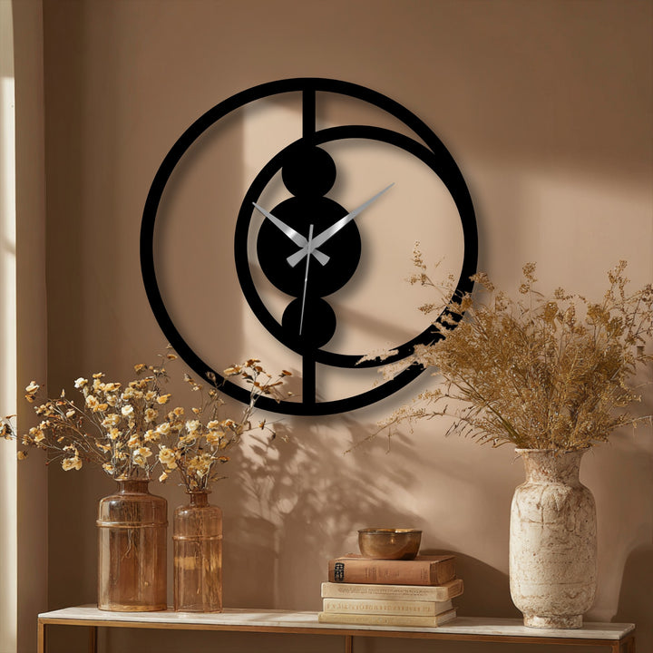 Sharp color contrast highlights the black abstract circular decorative metal art wall clock against the neutral-toned wall, creating a striking modern home decor statement.