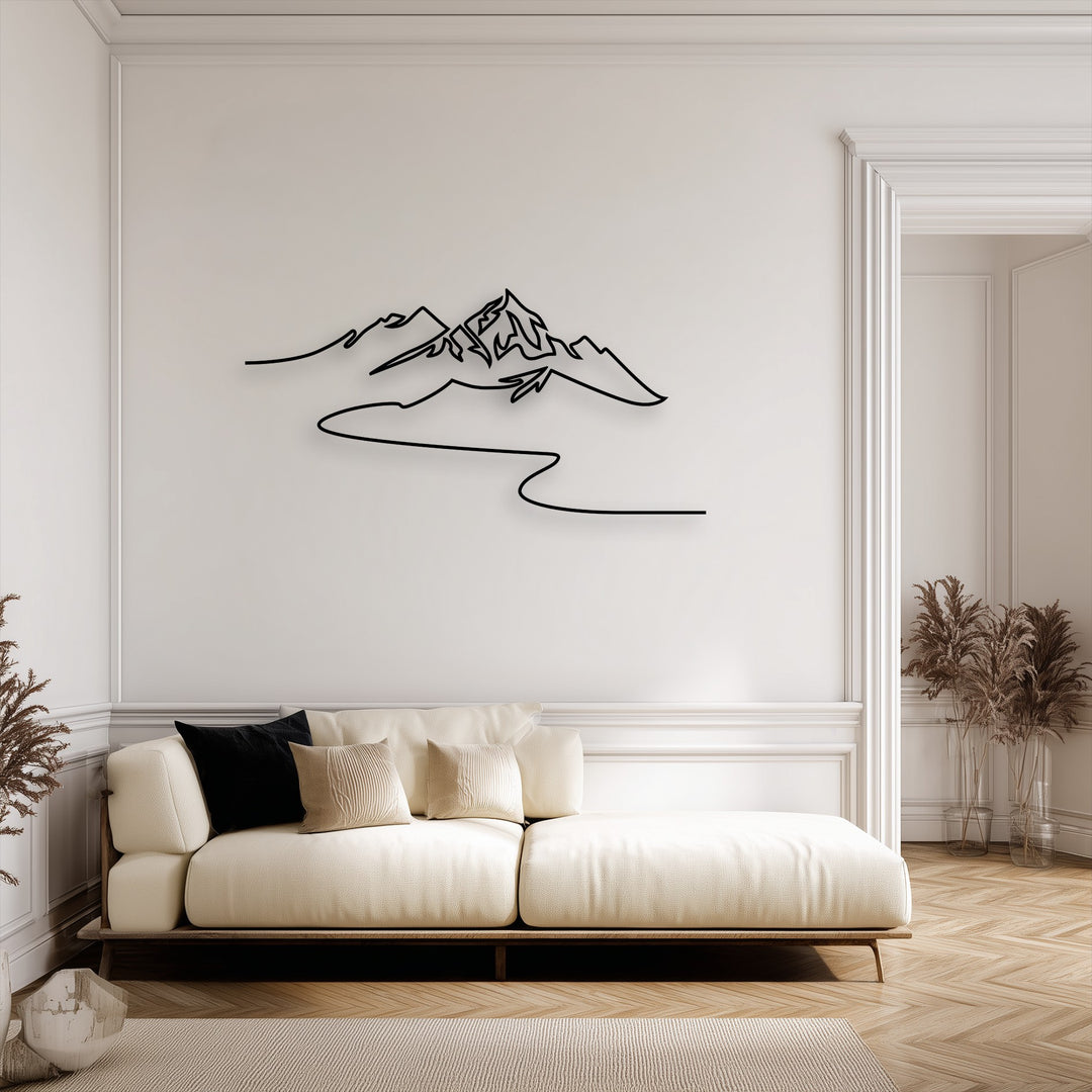 The brightest area features black minimalist mountain line art, a modern metal wall decor piece, on a pristine white wall above a light cream sofa.