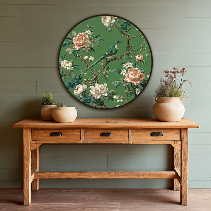 Featuring the edge and borders of an Emerald Songbird Among Blossoms Round oil painting art piece with a dark wood frame, mounted on a green paneled wall.