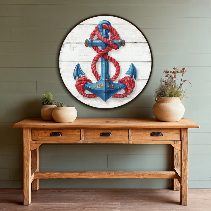 The hand-painted nautical anchor, the central subject of this oil painting art piece, is encircled by a vibrant red rope against a weathered, wooden background.