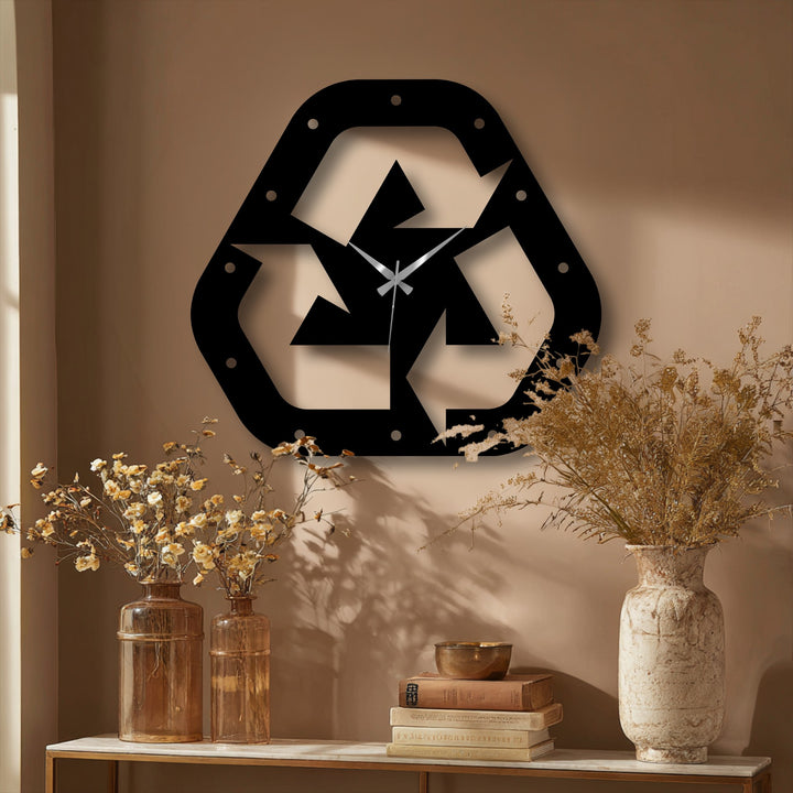 Recycle symbol decorative metal art, a wall clock featuring a minimalist, eco-modern design, boldly adorns the wall above vases and books.