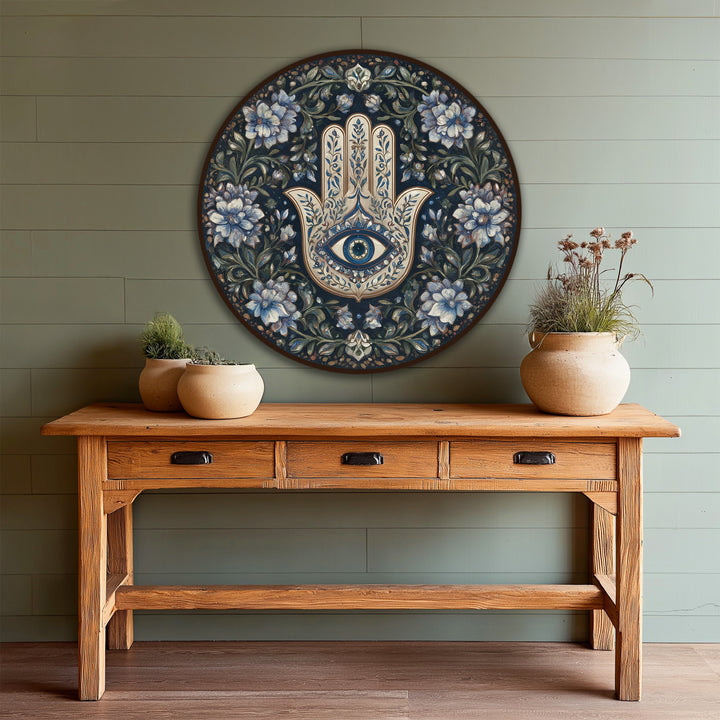 Subtle light and shadow play across the symbolic, hand-painted design in this round floral Hamsa protection, creating depth in this modern oil painting art piece on wood.