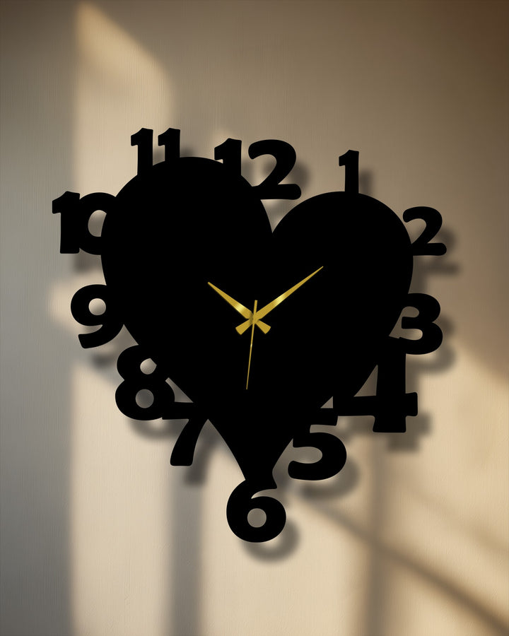 Dominant black heart-shaped metal artwork wall clock featuring distinct numbers and golden hands, casting shadows on a warm beige wall.