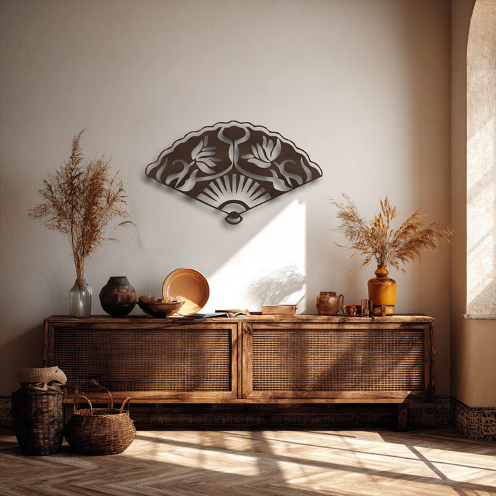 Warm sunlight creates a smooth transition of colors across the wall behind the dark Oriental fan metal wall decor.