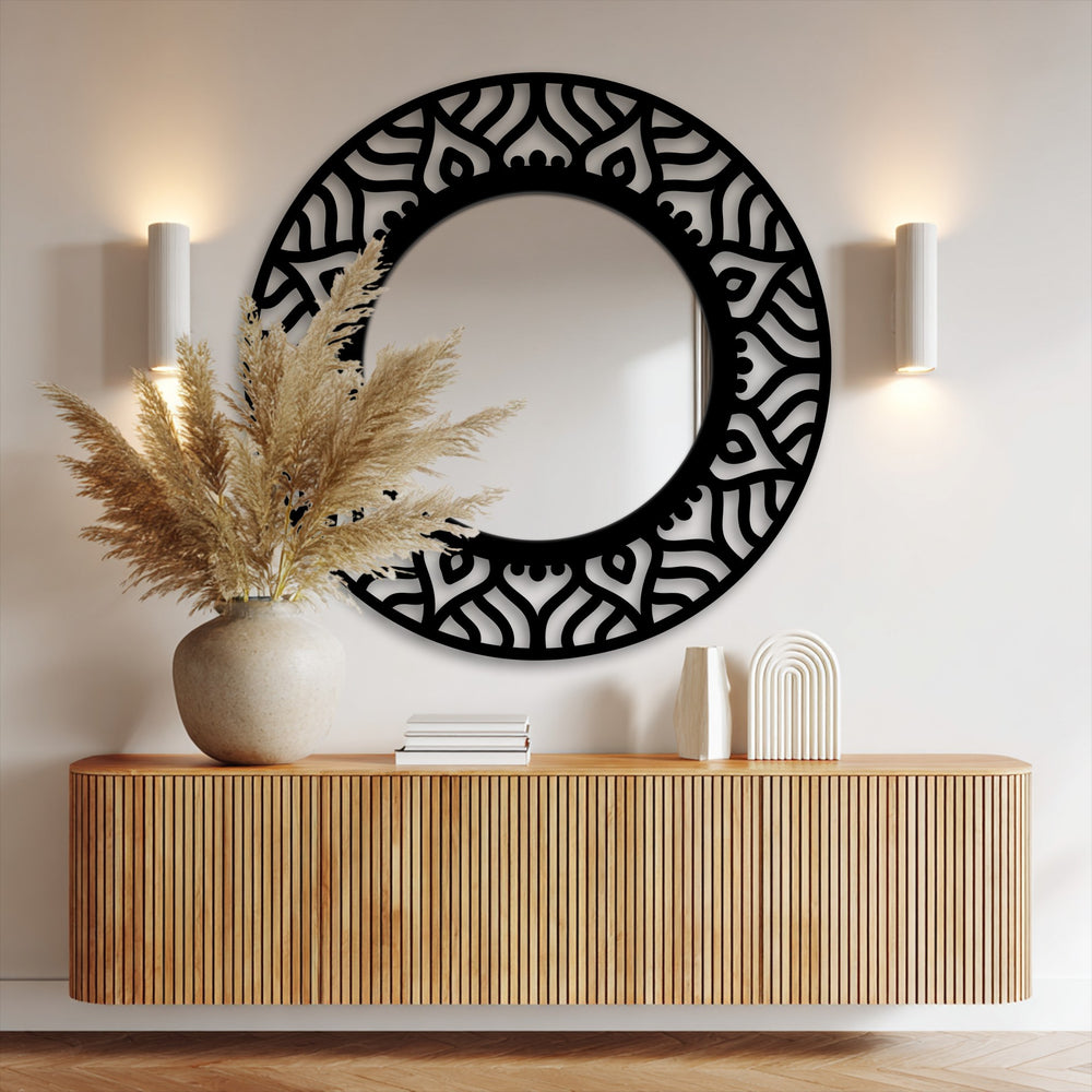 Warm color temperature illuminates the modern black metal statement design of the abstract pattern round floor mirror, enhancing a cozy atmosphere for decorating with wall mirrors.