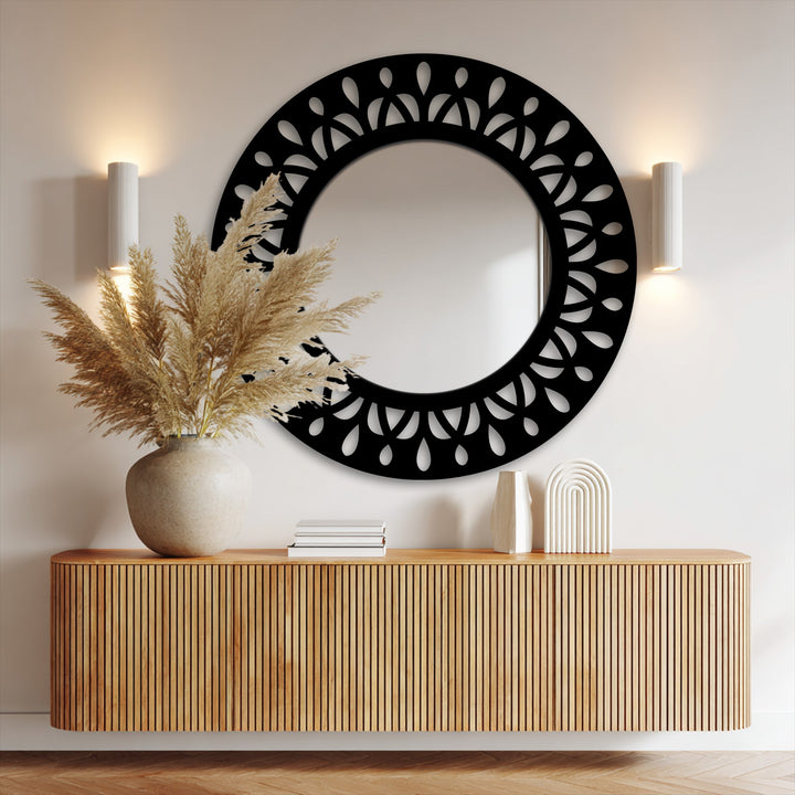 The realistic detail showcases the intricate black metal leaf motif of this decorative mirror, beautifully reflecting the room's subtle textures.