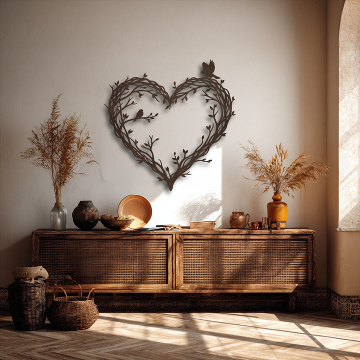 A textured beige wall subtly highlights the elegant heart-shaped bird and branch metal wall decor, casting soft shadows.