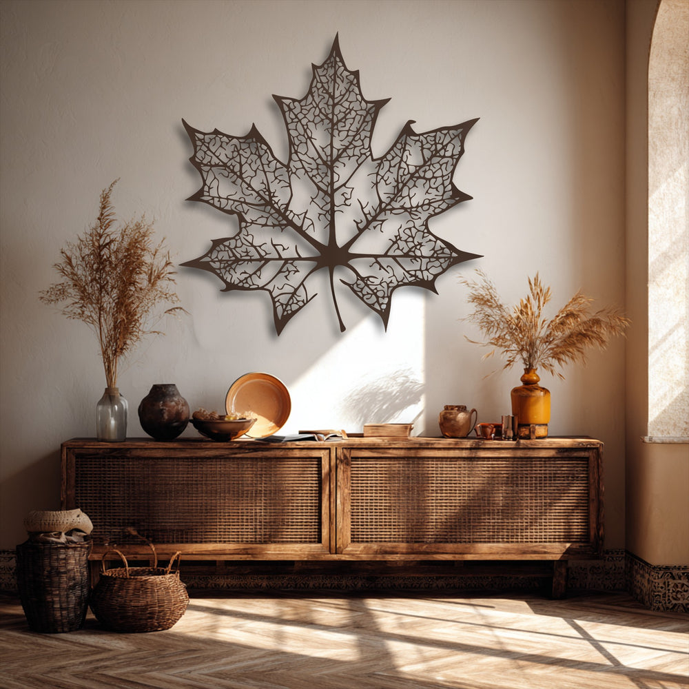 Sunlight beautifully highlights the intricate vein details of the large maple leaf decorative metal art, creating sharp shadows on the light-colored wall.